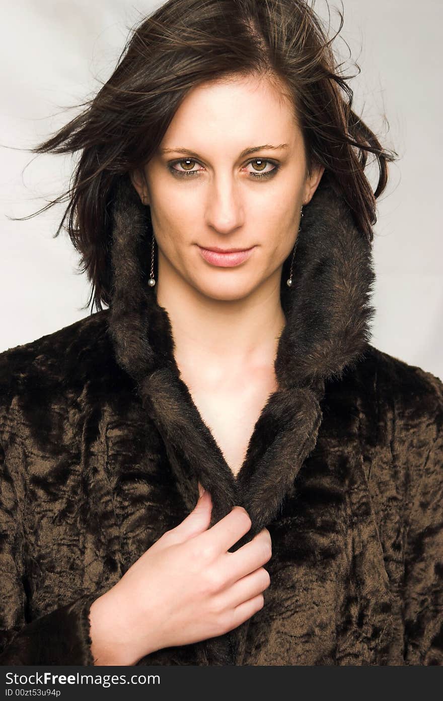 Attractive young female with flowing dark brown hair wearing a brown mock-fur coat. Attractive young female with flowing dark brown hair wearing a brown mock-fur coat.