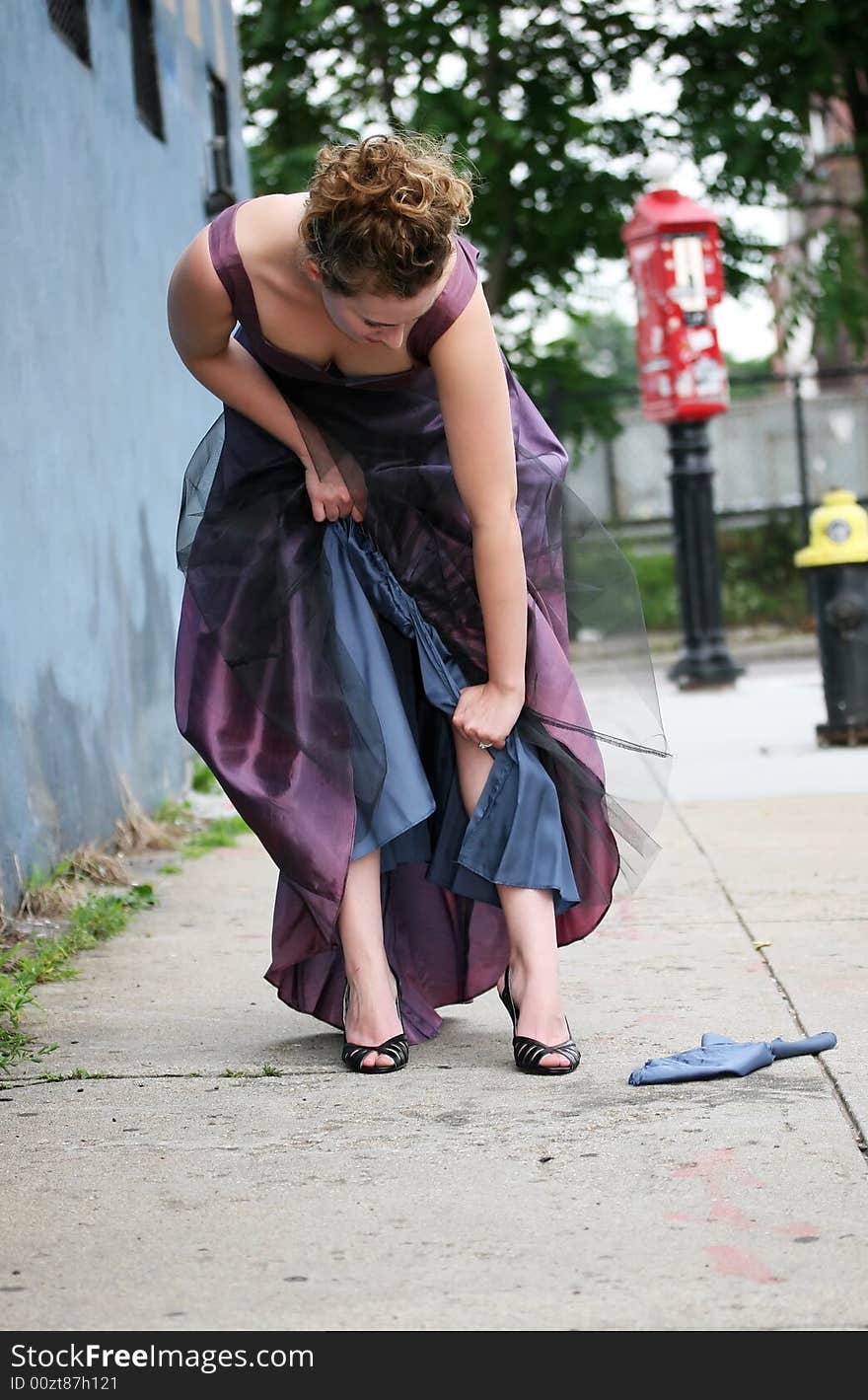 A woman tearing her bridesmaids dress on the street. A woman tearing her bridesmaids dress on the street