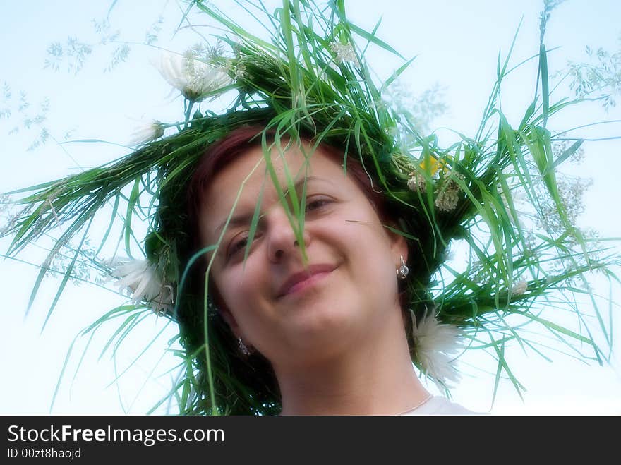 The young woman with a wreath from grasses and colours on a head. The young woman with a wreath from grasses and colours on a head