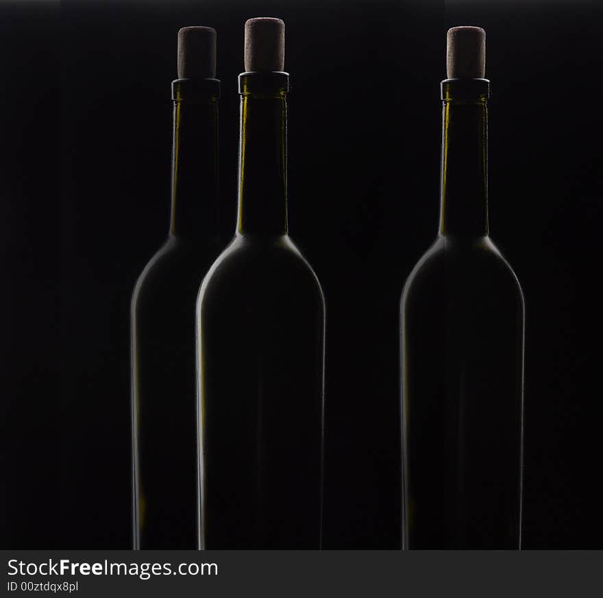 Three bottles of wine with a fuse on a black background