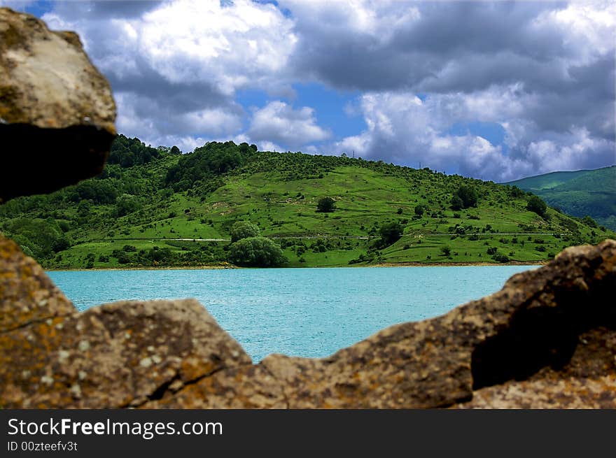 A view of mountain landscape with a small lake and some rocks. A view of mountain landscape with a small lake and some rocks