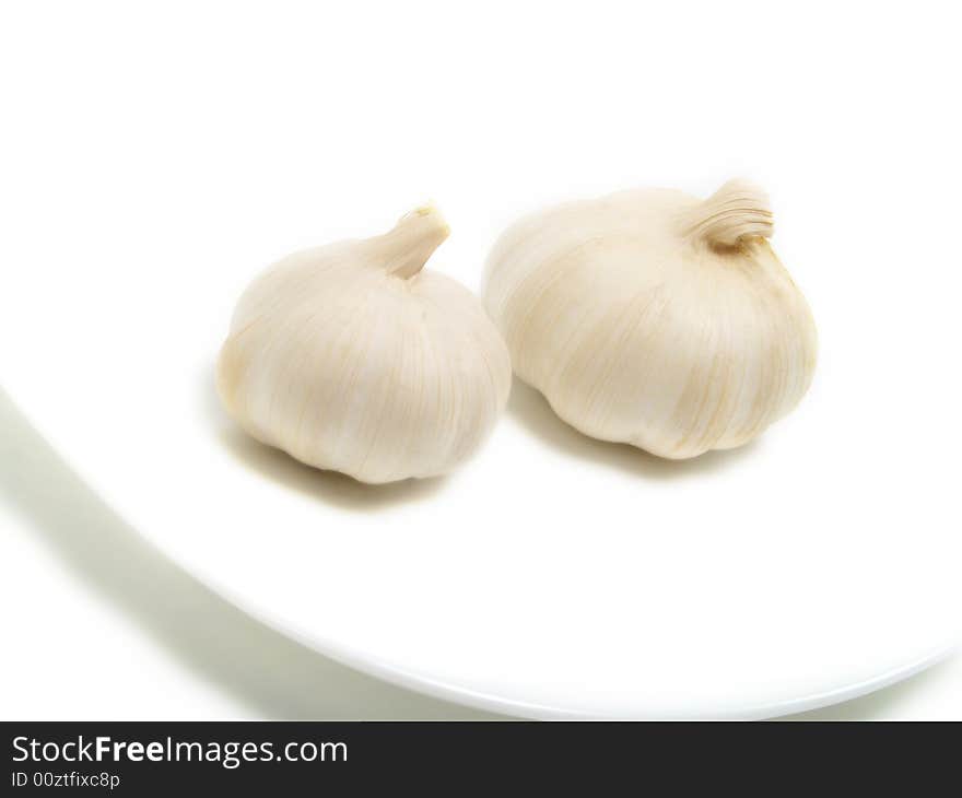 Two bulbs of garlic on white plate and isolated on white background. Two bulbs of garlic on white plate and isolated on white background