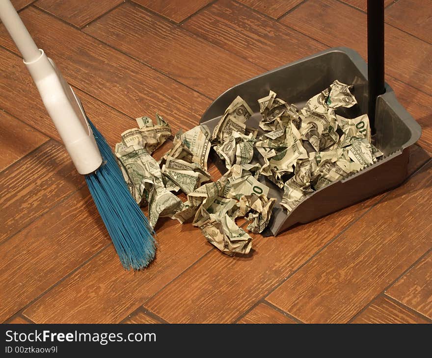 Photo of  a broom and dust pan sweeping up money. Photo of  a broom and dust pan sweeping up money