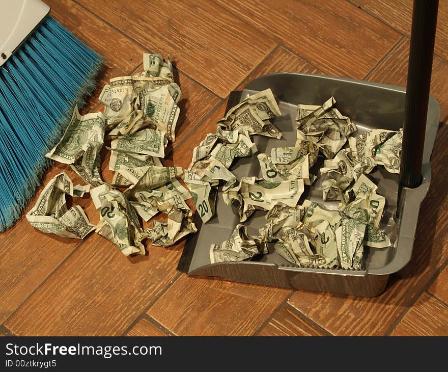 Photo of a broom and dust pan sweeping up money. Photo of a broom and dust pan sweeping up money