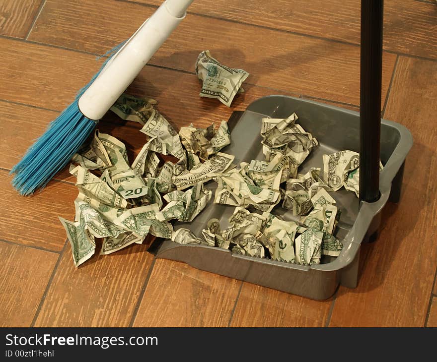 Photo of a broom and dust pan sweeping up money. Photo of a broom and dust pan sweeping up money