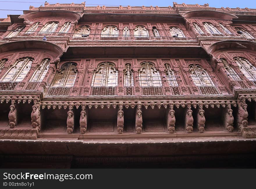 Wide windows, sculpted pillars arches and balconies on this red sand stone front of a palace in Bikaner, Rajasthan, India. Wide windows, sculpted pillars arches and balconies on this red sand stone front of a palace in Bikaner, Rajasthan, India.