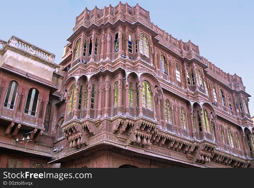 Wide windows, sculpted pillars arches and balconies on this red sand stone front of a palace in Bikaner, Rajasthan, India. Wide windows, sculpted pillars arches and balconies on this red sand stone front of a palace in Bikaner, Rajasthan, India.