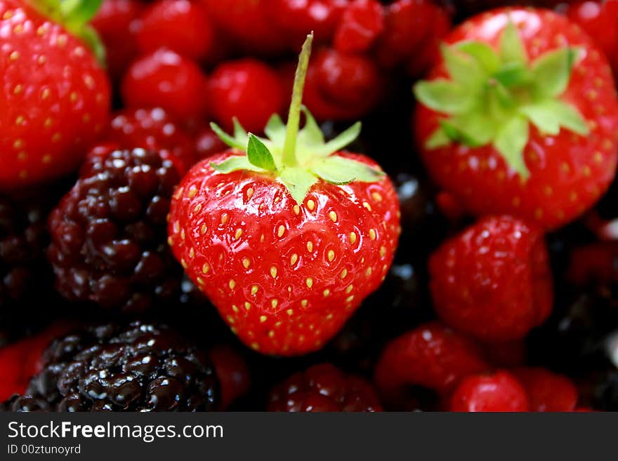 Close-up of a ripe strawberry on a background of mixed fruit. Close-up of a ripe strawberry on a background of mixed fruit