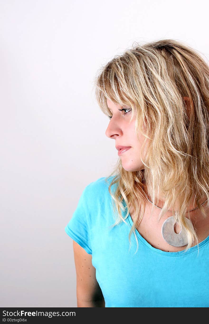 Blond Female model on a white background wearing a blue top. Blond Female model on a white background wearing a blue top