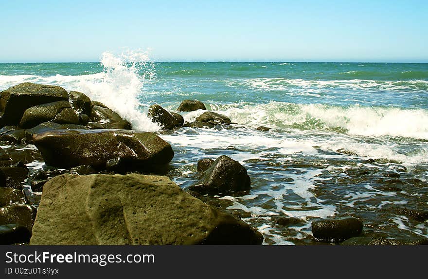 Waves Break on the Rocky Shore of a Blue-Green Sea. Waves Break on the Rocky Shore of a Blue-Green Sea