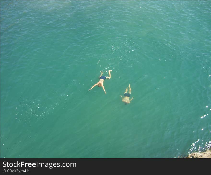 Jump from a high rock in water and swim in the sea