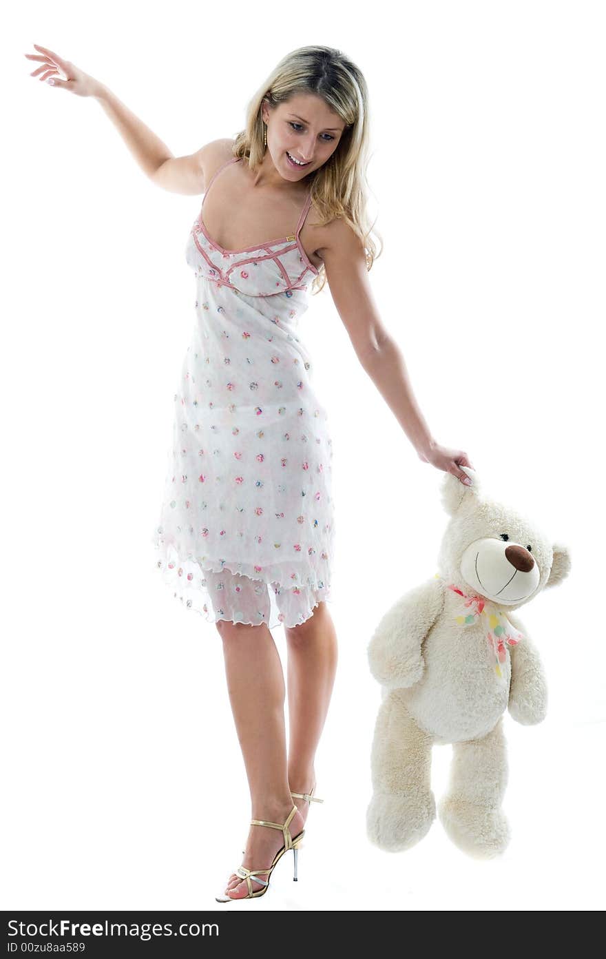 The young charming girl plays with a bear