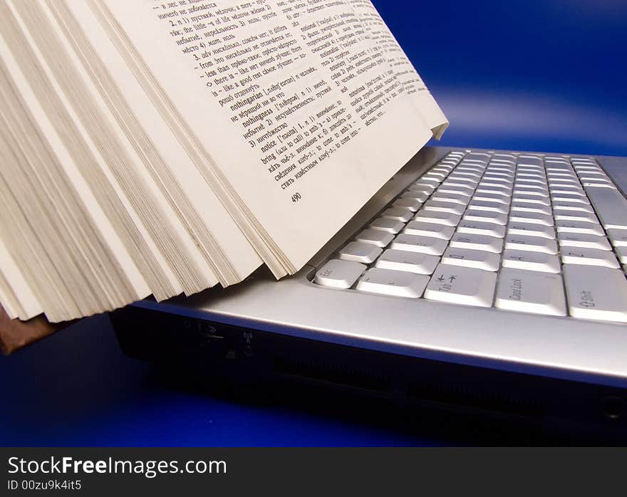 Book on laptop on blue background