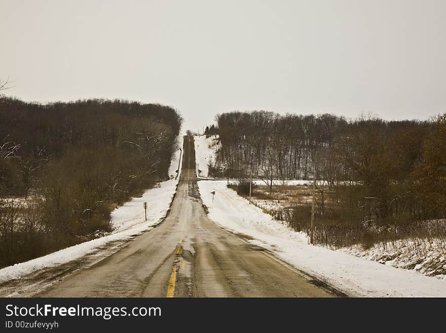 Rural road bordered by snow and trees. Rural road bordered by snow and trees