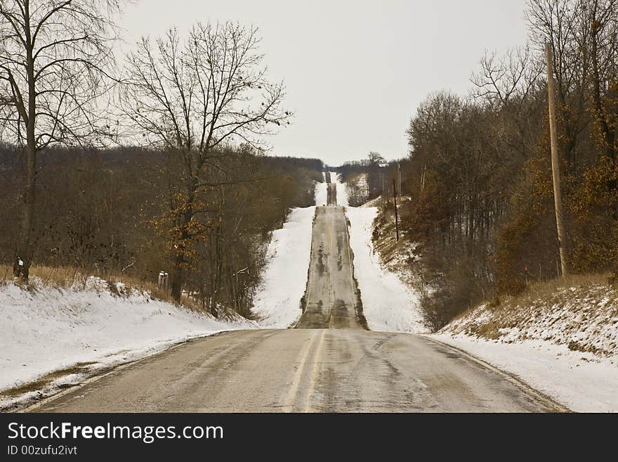 Rural midwestern winter road bordered by woods. Rural midwestern winter road bordered by woods