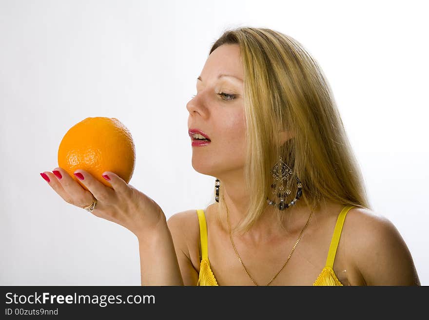 Blonde woman in yellow dress with orange in her hand. Blonde woman in yellow dress with orange in her hand