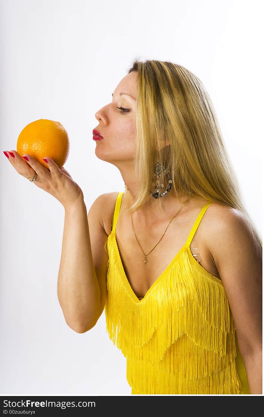 Blonde woman in yellow dress with orange in her hand. Blonde woman in yellow dress with orange in her hand