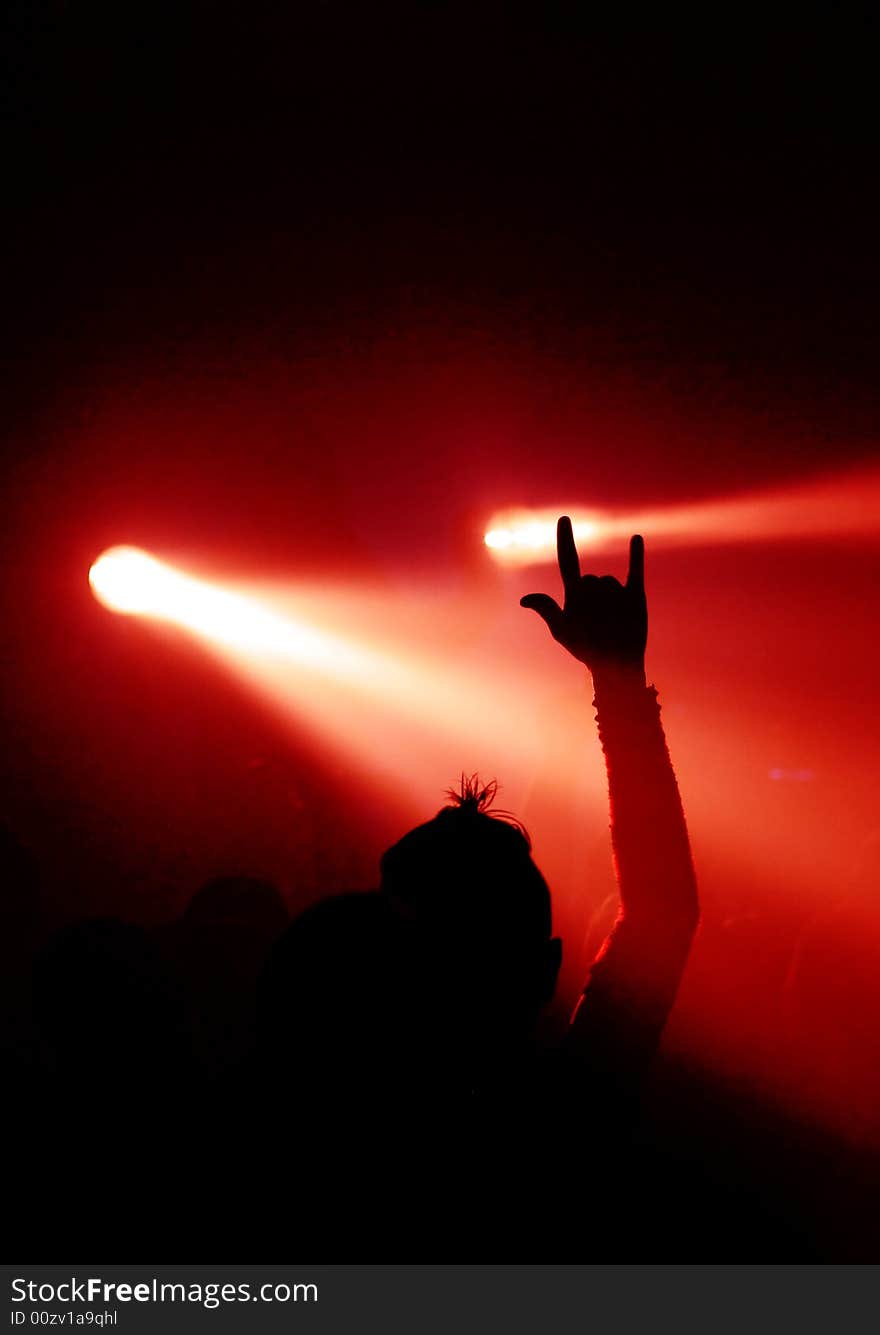 Music fan showing devil sign with hand in front of two lights. Music fan showing devil sign with hand in front of two lights