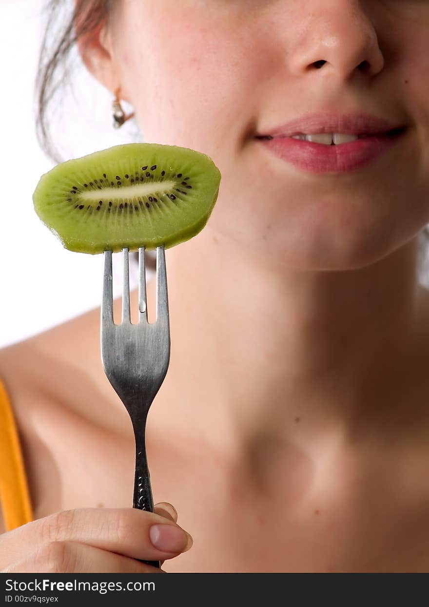 Beautiful caucasian teen eats kiwi with fork. Beautiful caucasian teen eats kiwi with fork