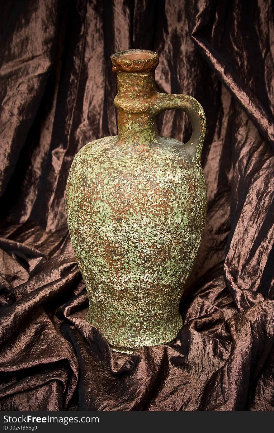 Ancient wine jug on brown hangings