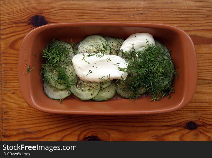 Cucumber salad with sour cream in brown ceramic cup