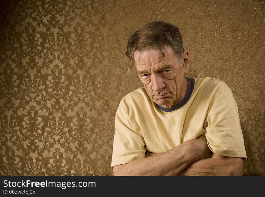 Senior Man Against a Gold Background with a Stern Expression and Arms Crossed. Senior Man Against a Gold Background with a Stern Expression and Arms Crossed