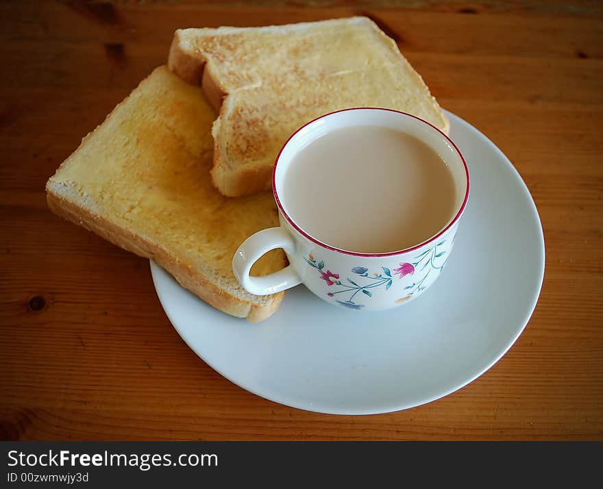 A cup of milk, bread and butter in a wooden table. A cup of milk, bread and butter in a wooden table