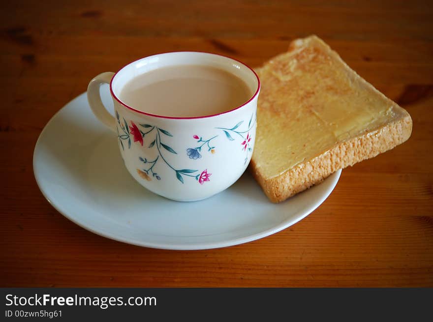 A cup of milk, bread and butter in a wooden table. A cup of milk, bread and butter in a wooden table