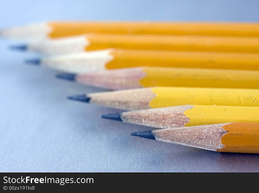 Seven Sharpened pencils in a row on grey background