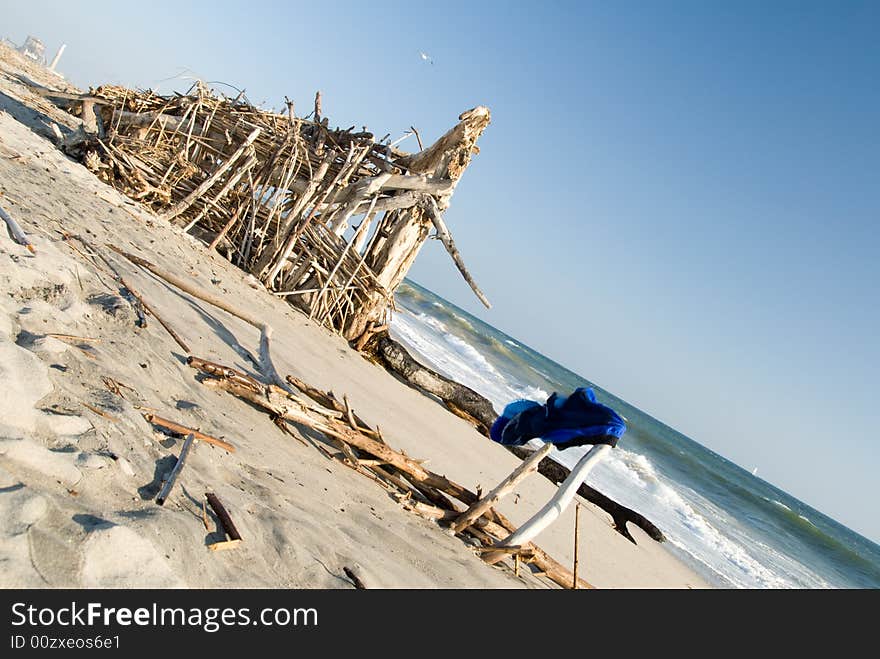 Shorts hung on a branch in the foreground to dry and a driftwood shelter in the mid ground and the ocean and a power plant in the background. Shorts hung on a branch in the foreground to dry and a driftwood shelter in the mid ground and the ocean and a power plant in the background