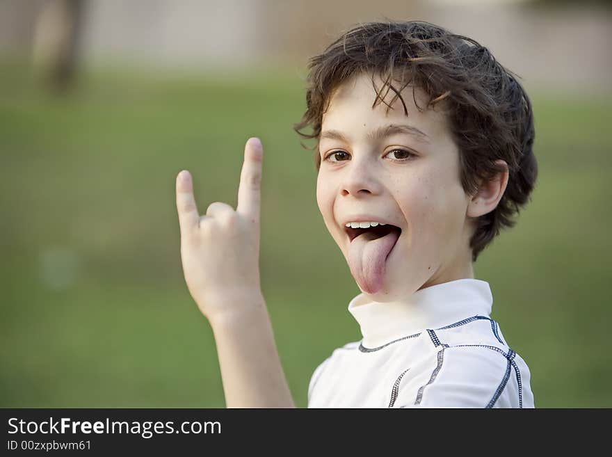 Boy sticking out his tongue and making a bull horn gesture with his hand. Boy sticking out his tongue and making a bull horn gesture with his hand