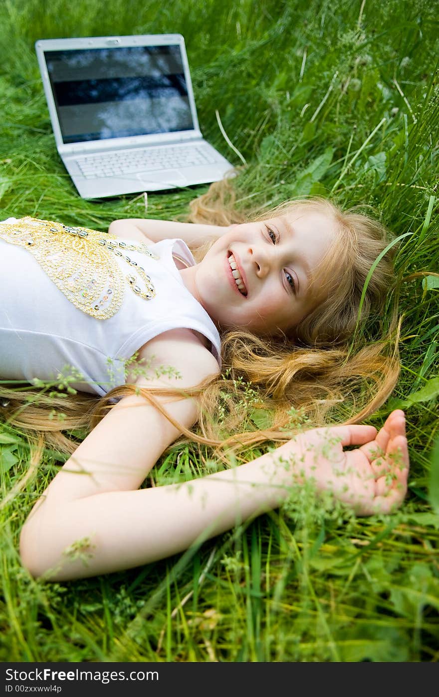 Smiling little girl with laptop in green grass. Smiling little girl with laptop in green grass