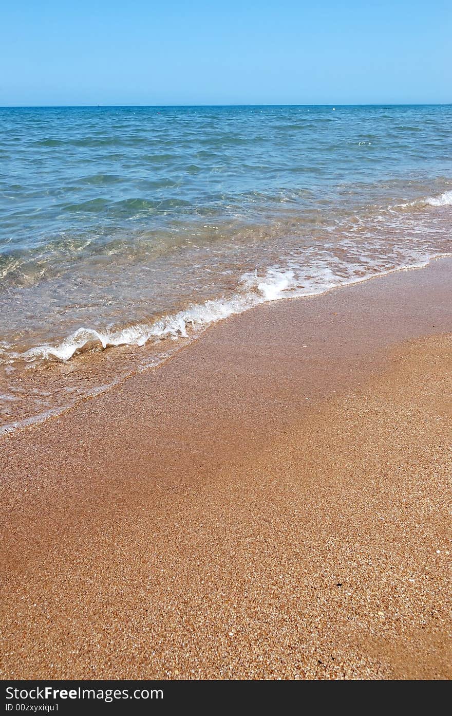 The point where the sea meets the sand on a sunny day at the beach. The point where the sea meets the sand on a sunny day at the beach