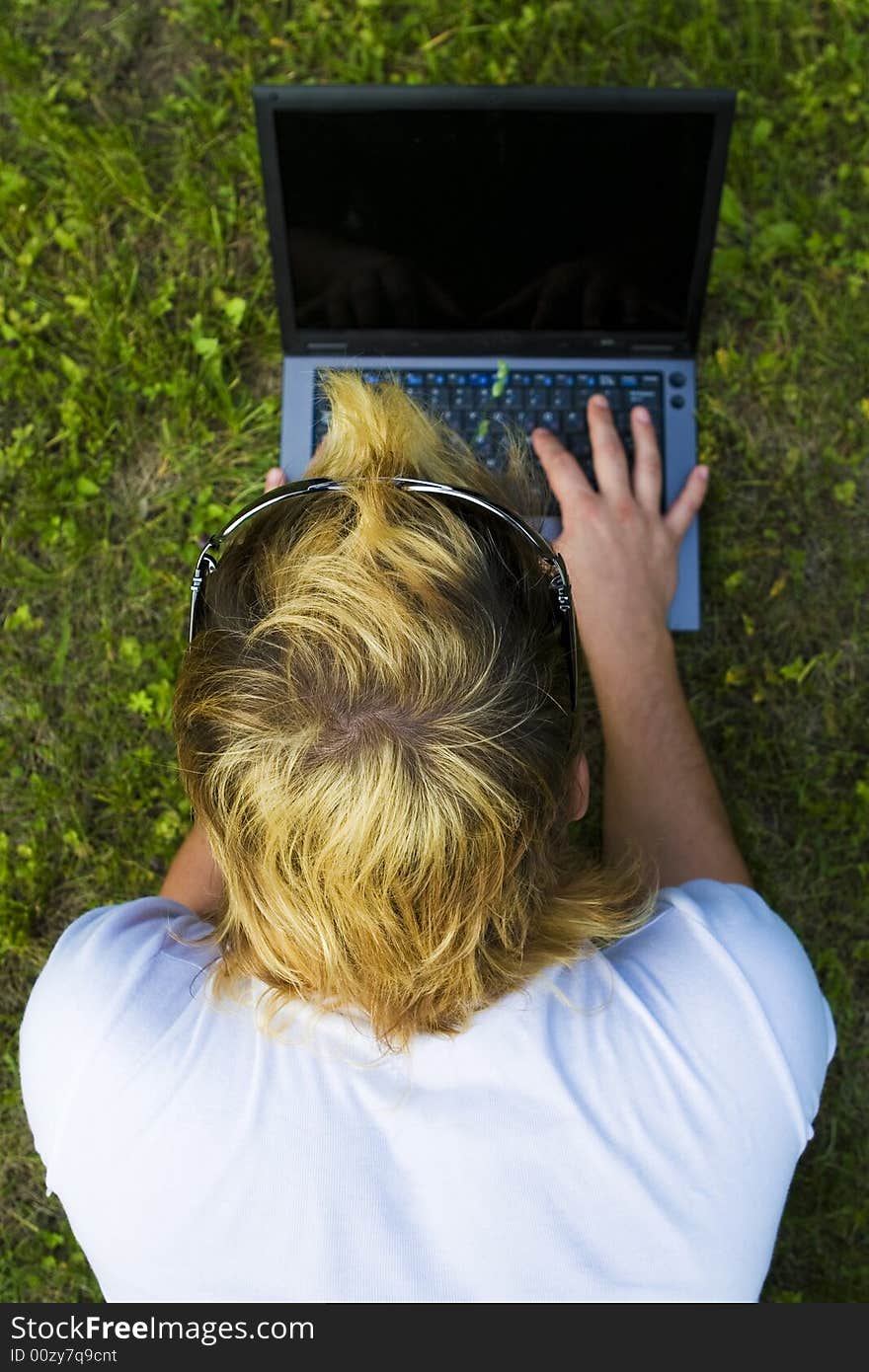 Casual man works on laptop on the grass