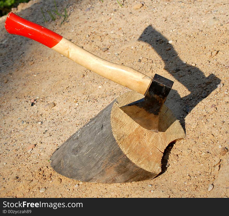 Axe in a tree on background of sand