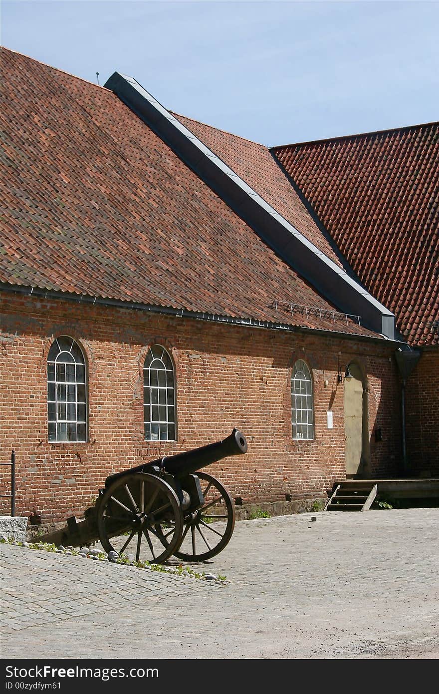 An old canon outside an old brick building. An old canon outside an old brick building