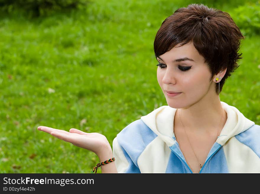 Attractive girl on a background of a green grass holds a hand a palm upwards. Attractive girl on a background of a green grass holds a hand a palm upwards