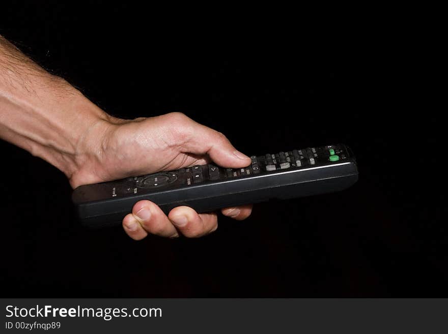 Hand of man holding remote control - low key. Hand of man holding remote control - low key