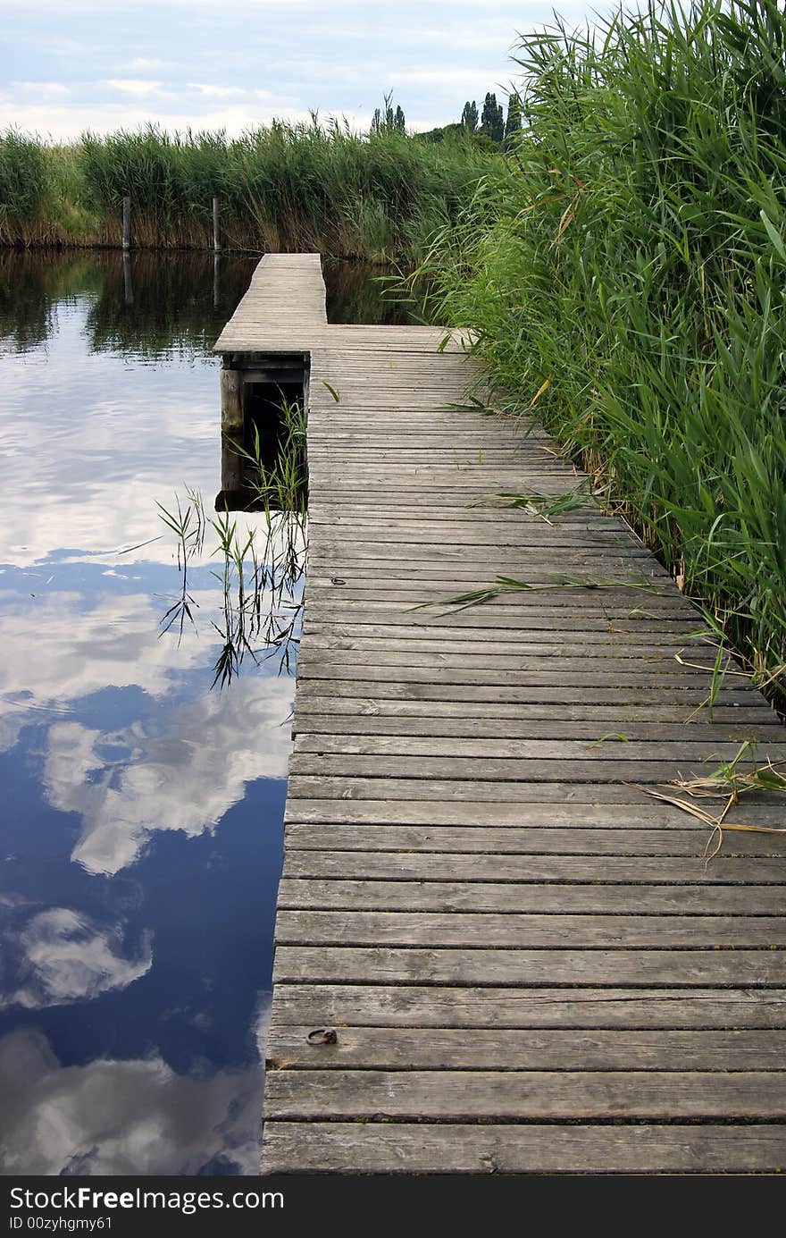 Wooden footbridge in a lake, surrounded by reed. Wooden footbridge in a lake, surrounded by reed