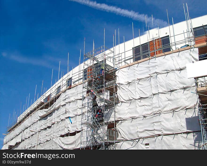 A general view of the exterior of a new modern building site development covered in scaffolding and cladding.