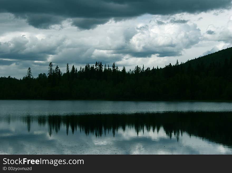 Silhouette of trees behind a silent lake. Silhouette of trees behind a silent lake