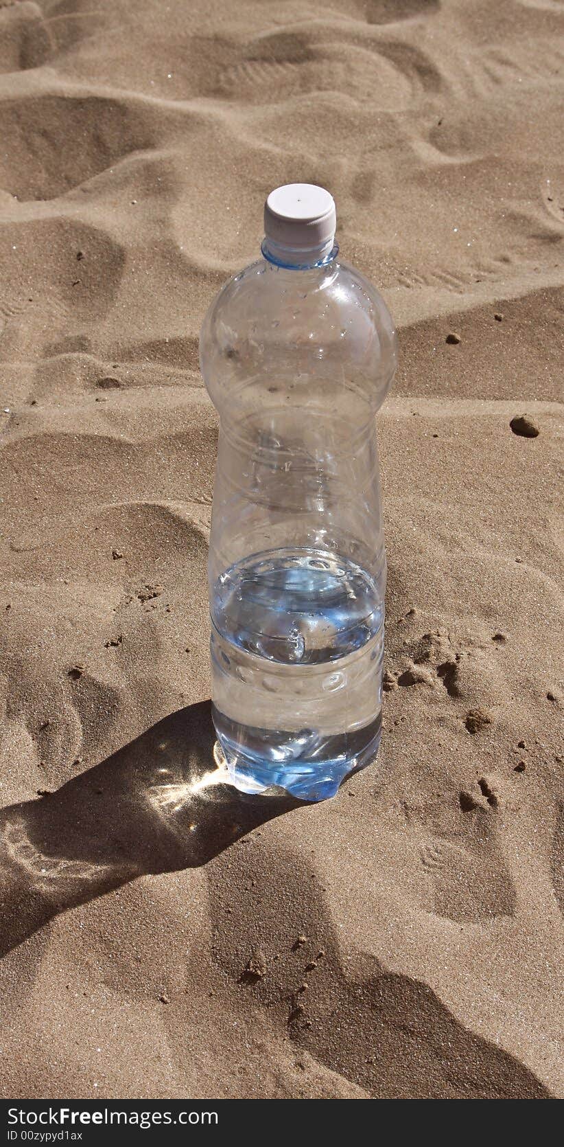 Plastic bottle with water on sand