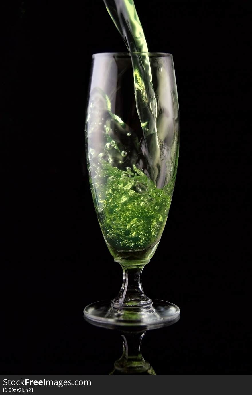 Glass of drink poured on black background