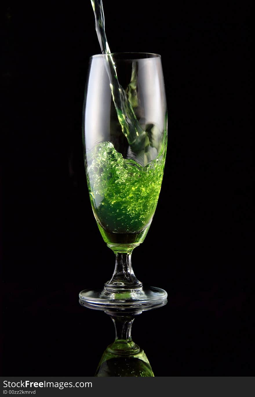 Glass of drink poured on black background