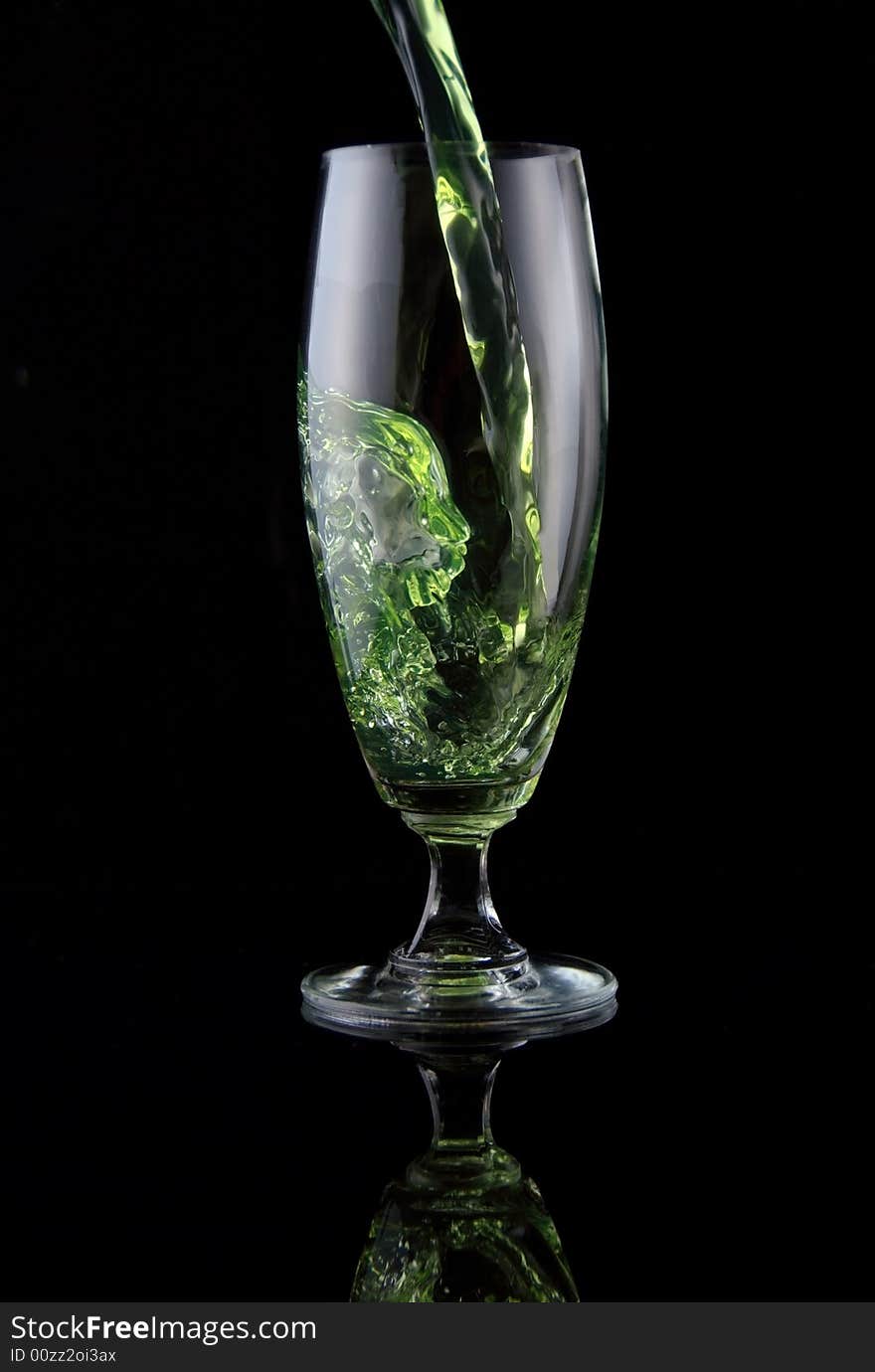 Glass of drink poured on black background