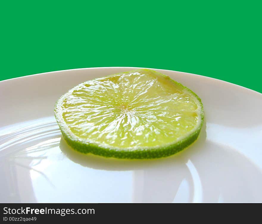 Piese of green lime on a white plate