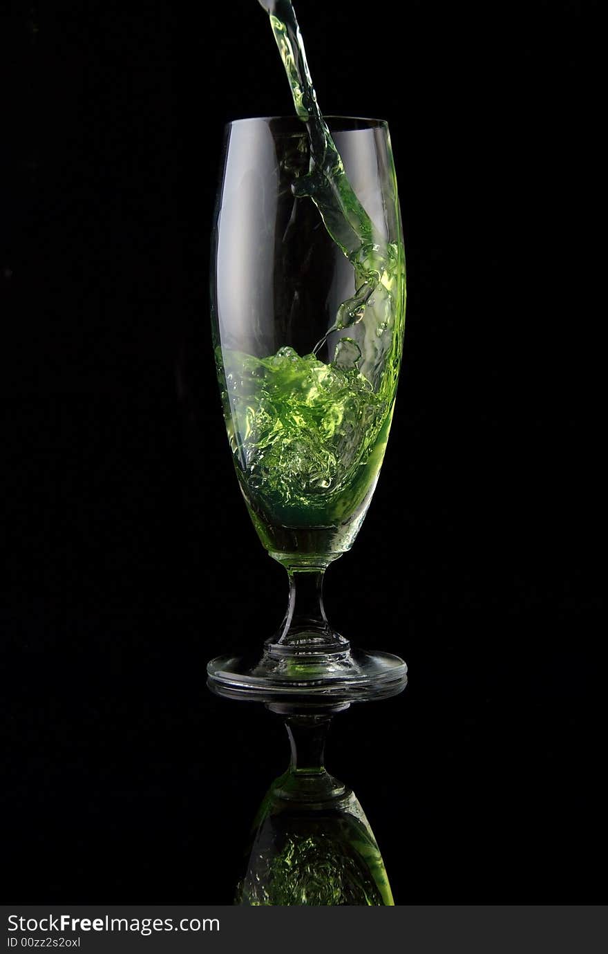 Glass of drink poured on black background