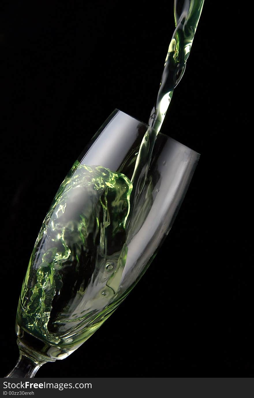 Glass of drink poured on black background