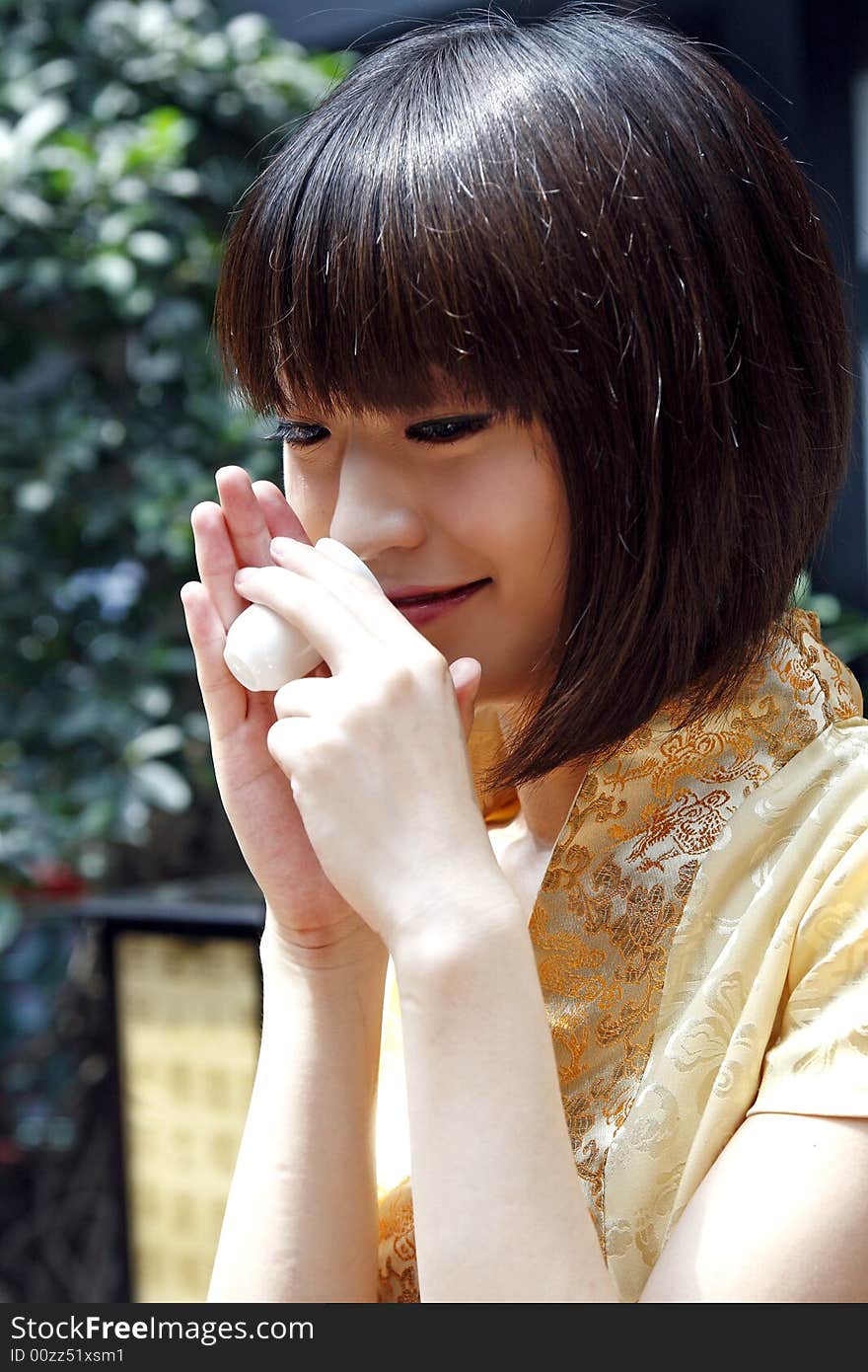 A Chinese girl is performing the tea art… Chinese characters on the lantern are the ancient poesy of China by the tree. A Chinese girl is performing the tea art… Chinese characters on the lantern are the ancient poesy of China by the tree.