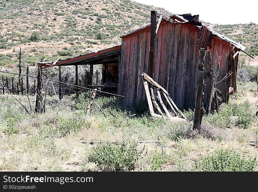 Abandoned ranch outbuilding in South West United States. Tin roof, weathered siding with wooden fencing and barbed wire. Mountain location in Arizona. Abandoned ranch outbuilding in South West United States. Tin roof, weathered siding with wooden fencing and barbed wire. Mountain location in Arizona.